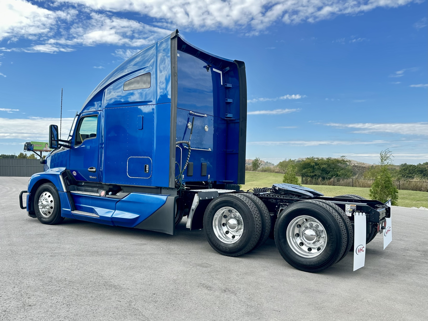 Kenworth T680 tractor cabin side view showing blue exterior and rear dual-axle with chrome wheels.