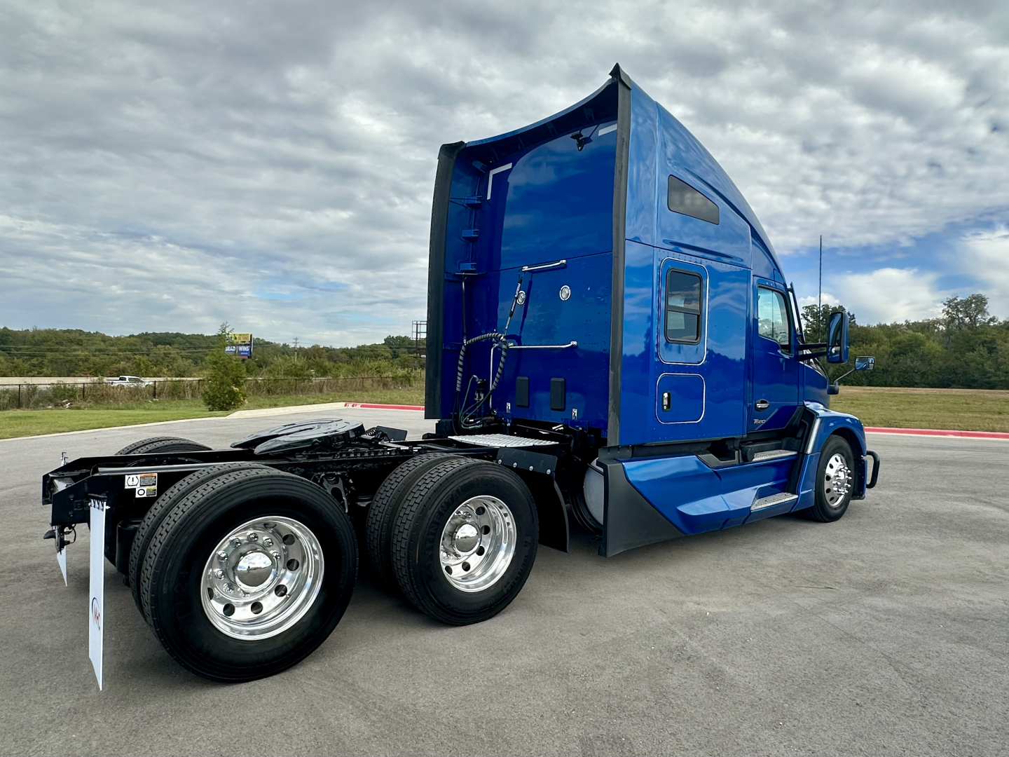 Kenworth T680 truck twin rear axles and blue sleeper cab side view showing wheels and chassis.