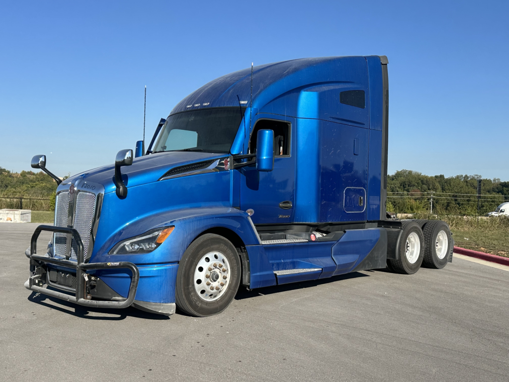 Kenworth T680 conventional sleeper tractor in blue, side view with front bull bar, single-axle drive near rear.