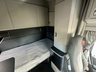 Interior sleeper area of a Kenworth T680 cab with bunk bed setup, visible mattress, and storage cabinet nearby.