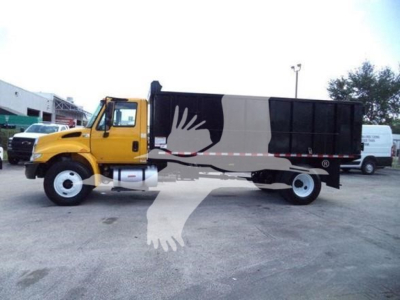 Truck in yard with yellow cab and black dump body, side view showing VIN/sticker area?