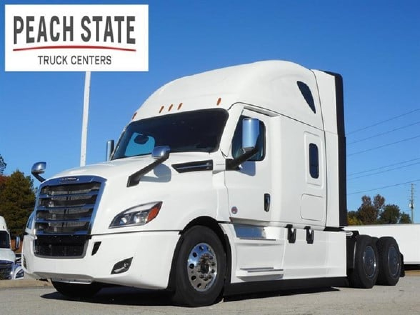 Freightliner Cascadia 126 tractor-trailer in white, single sleeper configuration, side view with Peach State Truck Centers sign in background.