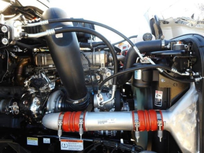 Freightliner Cascadia 126 engine bay showing turbo hoses, metallic coolant lines, and red hose clamps.