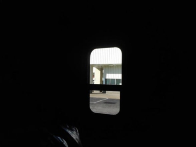 Freightliner Cascadia 126 truck interior view through small window, dark cabin with bright exterior building visible.