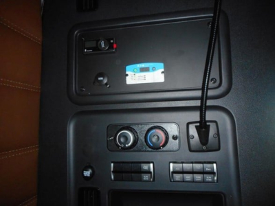 Dashboard control panel of a Freightliner truck showing climate controls, a 12V/USB area, and a microphone cord.