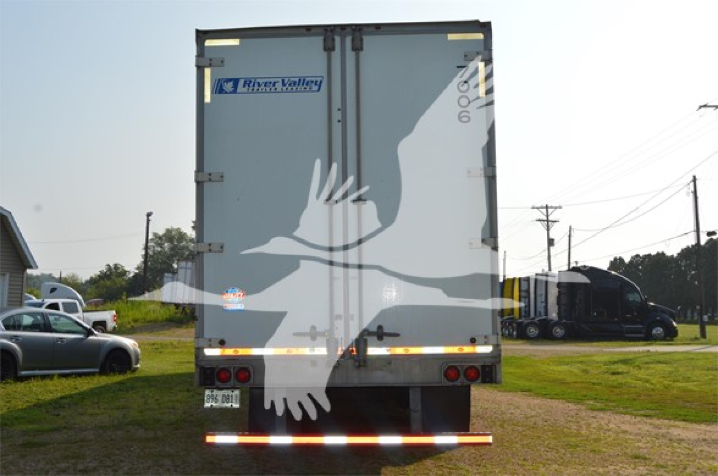 Utility 4000Dx trailer back view showing two rear doors and River Valley Transportation sticker, with brake lights and reflective bumper.