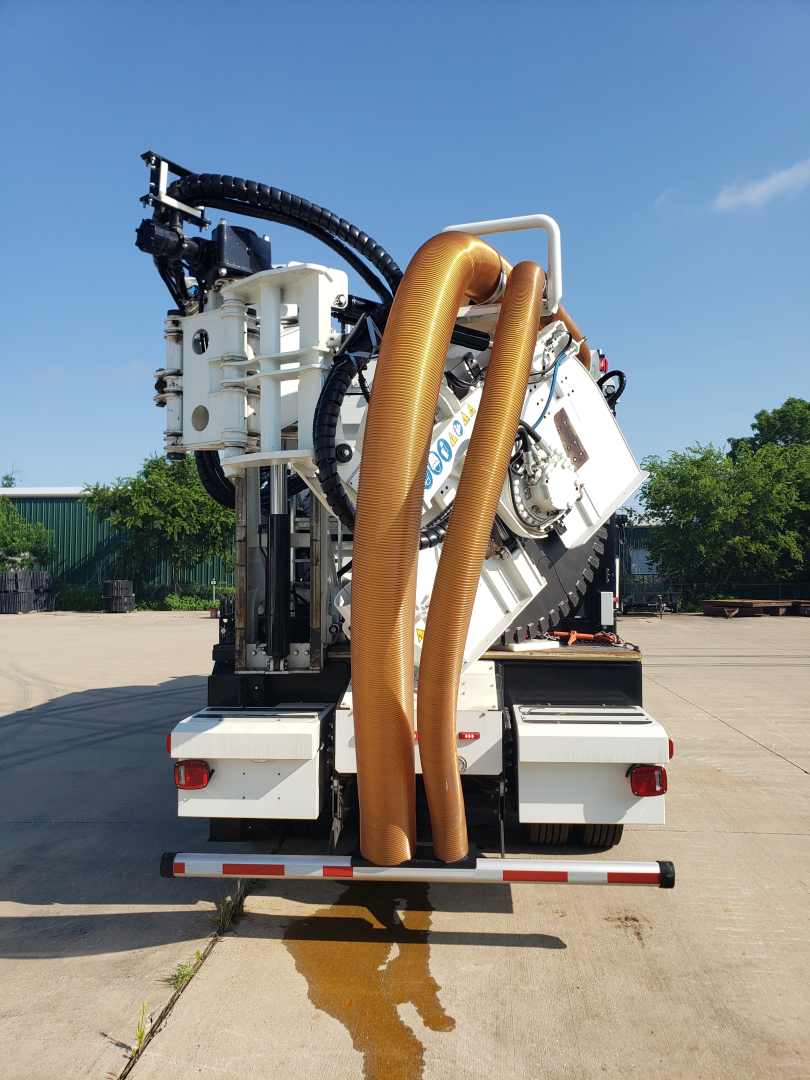 Back of a Volvo VHD86B300 trencher truck showing large orange flexible hoses and equipment mounted on a white chassis.
