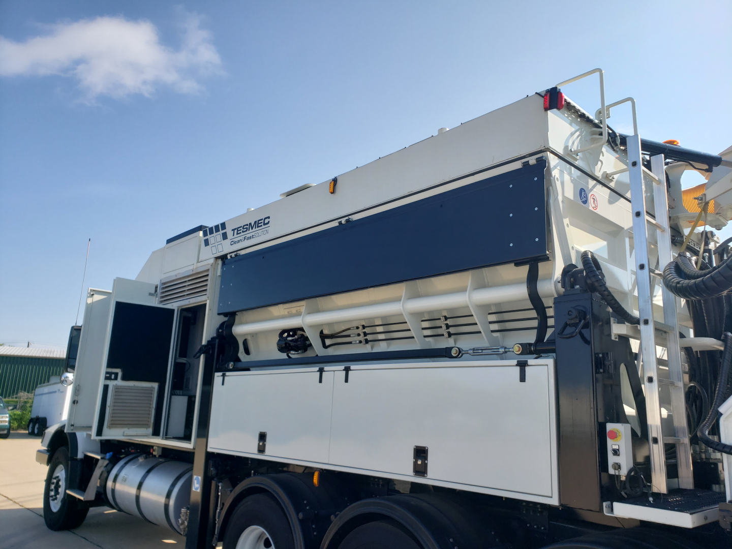 Volvo VHD86B300 trenching truck side view showing large white body with dark blue panel accents and toolbox doors, side tank, and rear work platform.