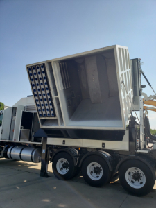 Tractor-trailer mounted industrial machine with large angled open hopper and multiple cylindrical tubes; Volvo VHD86B300 equipment on a haul truck.