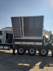 Volvo VHD86B300 truck in a lot showing a large trenching attachment on the rear with multiple pipes arranged in a grid on the side. three rear axles visible and chassis.