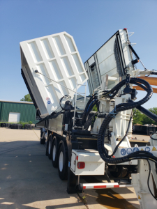 Volvo VHD86B300 truck with raised dump bed and hydraulic hoses, side view showing multiple axles and rear hitch.