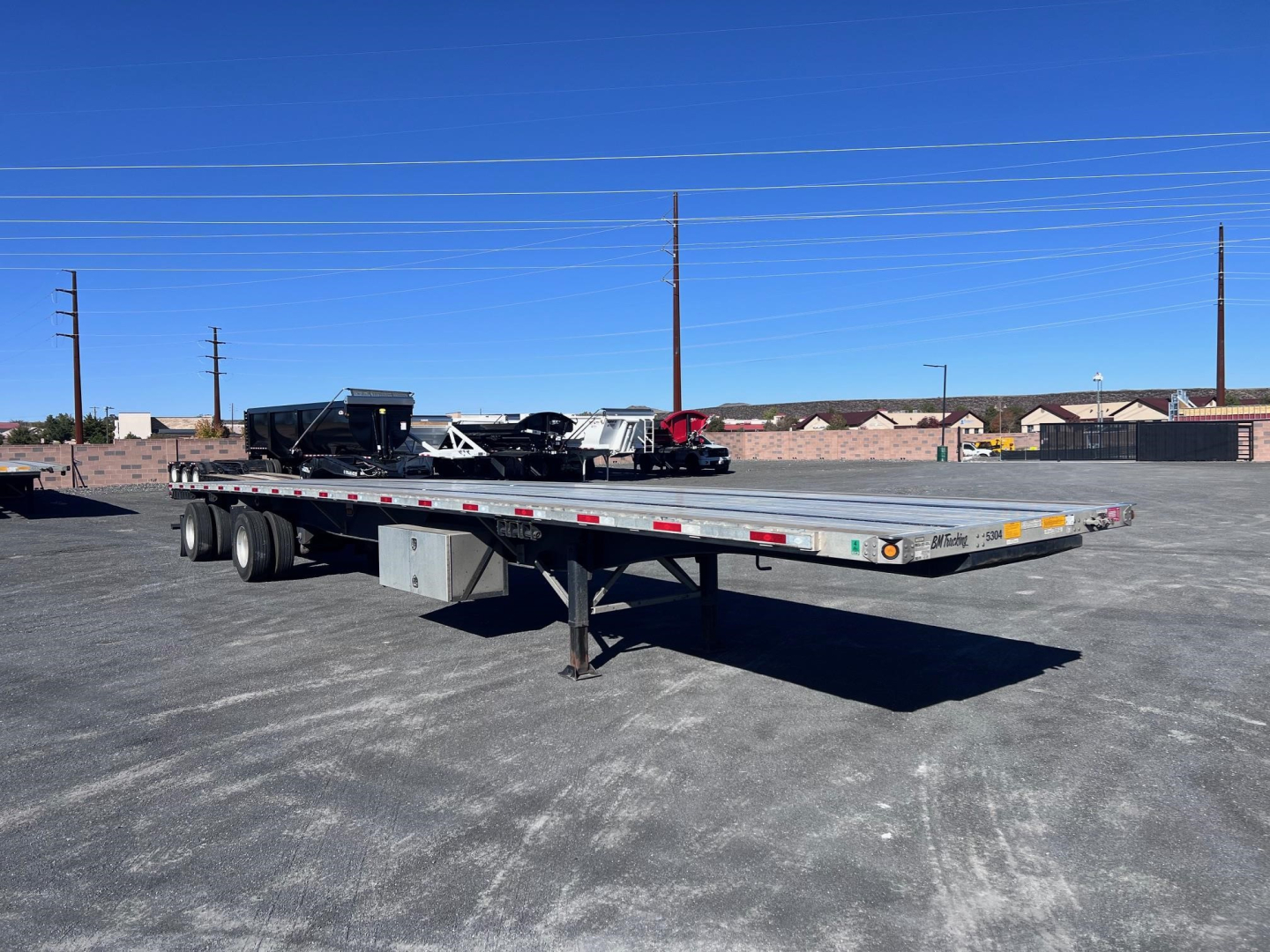 Utility 4000Ae flatbed trailer in a parking lot, view shows long flatbed with dual rear axles and a front landing gear, stock number 212705.