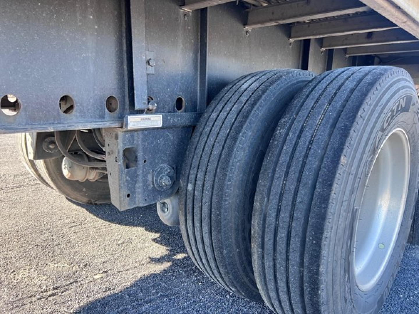 Trailer wheels and undercarriage showing dual rear tires and frame with mounting brackets.