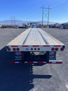 Utility 4000Ae flatbed trailer rear view showing long aluminum deck with reflectors and taillights.