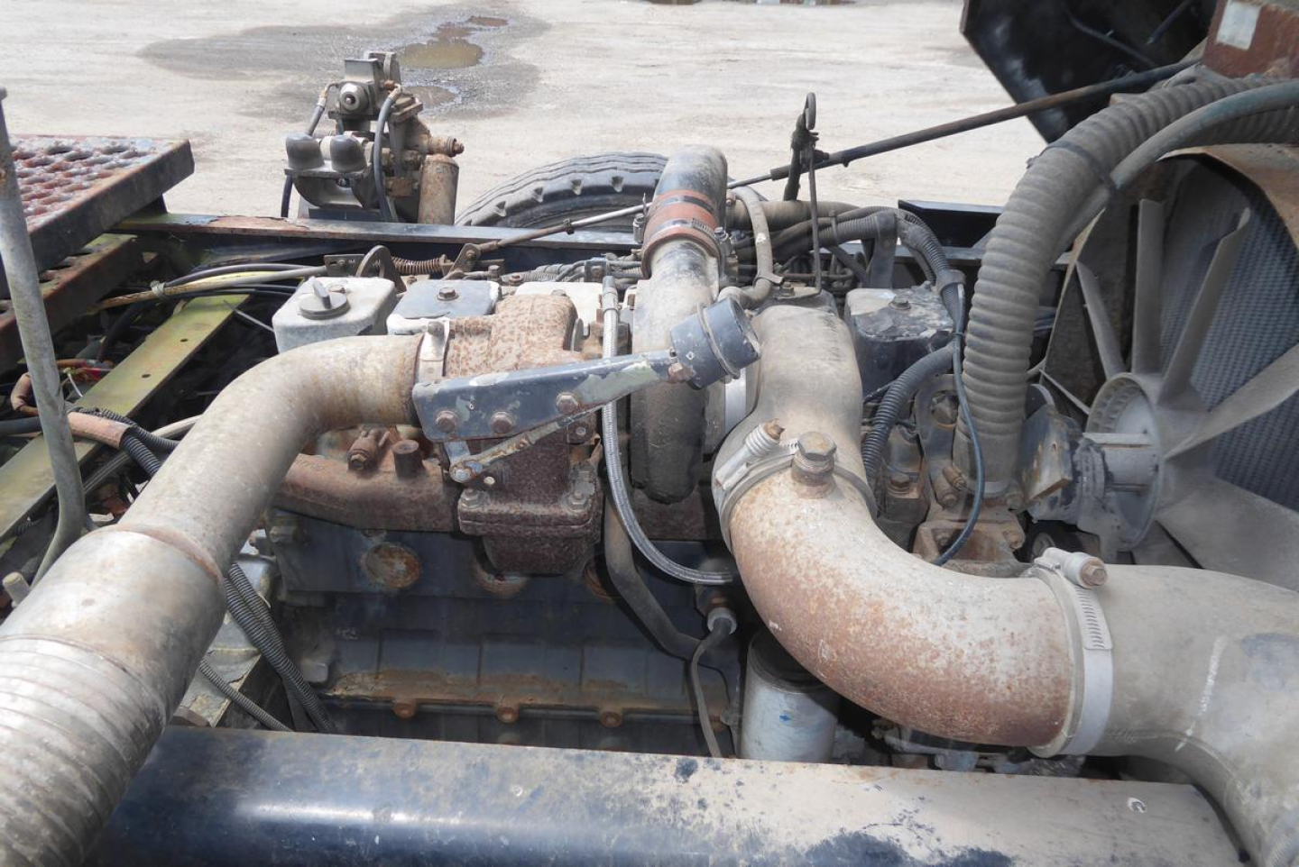 Truck engine bay showing large exhaust manifold and air intake piping in a used Ottawa yard truck.