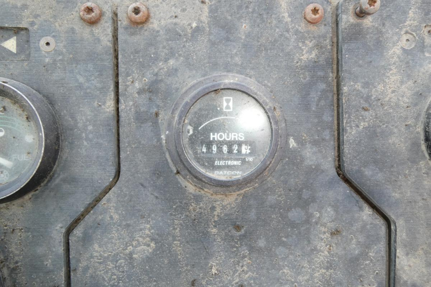 Panel of an industrial gauge cluster showing an hour meter reading 49627 hours, with other dials and worn metal surface.