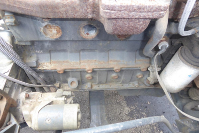 Engine bay of a used Ottawa 30 truck showing engine block with visible bolts, hoses, and a battery/alternator area.