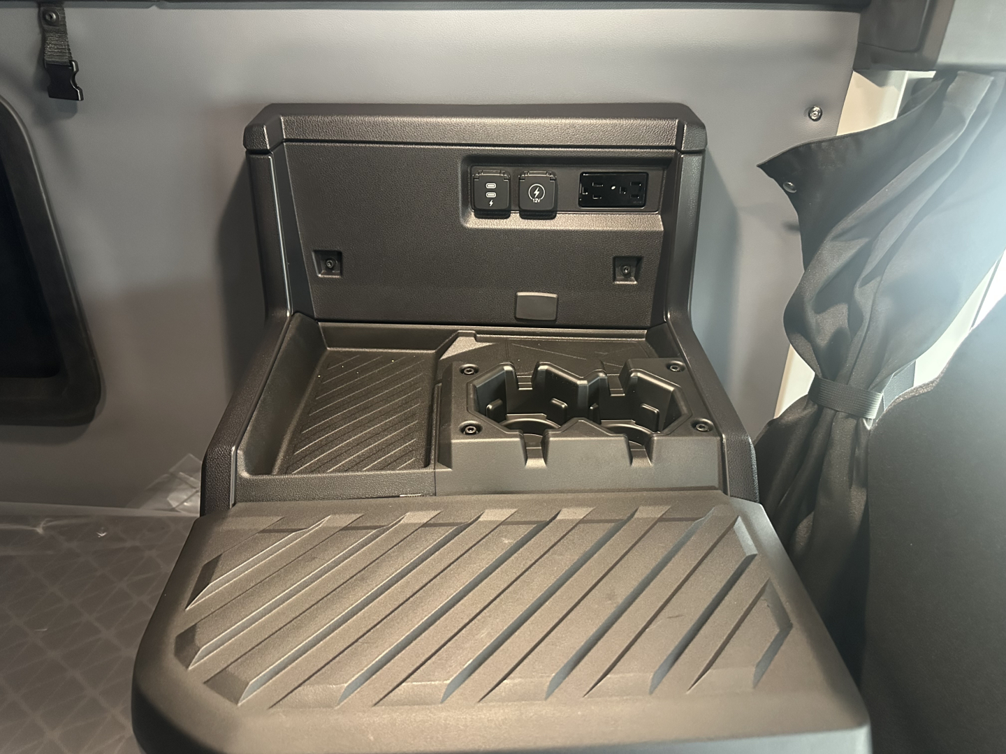 Cab interior center console showing cup holders and charging/auxiliary ports on the dash area, with a fold-out tray/table surface.