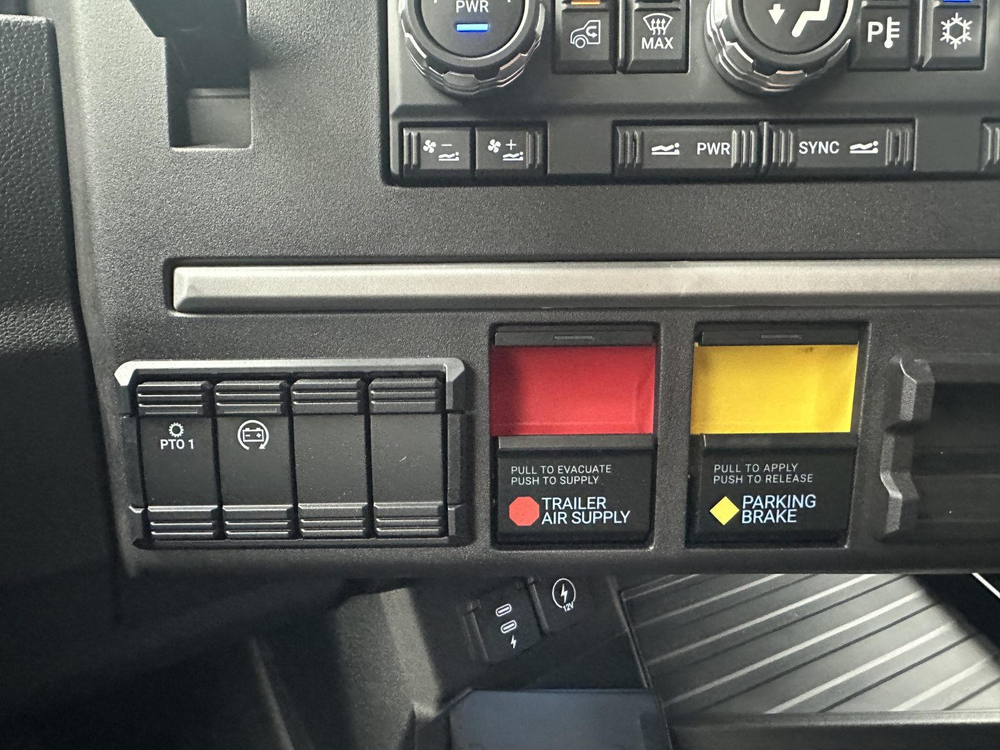 Dashboard area showing PWR controls and two colored switches (red and yellow) with labels 'Trailer Air Supply' and 'Parking Brake' in a Mack PR64T76H cab.
