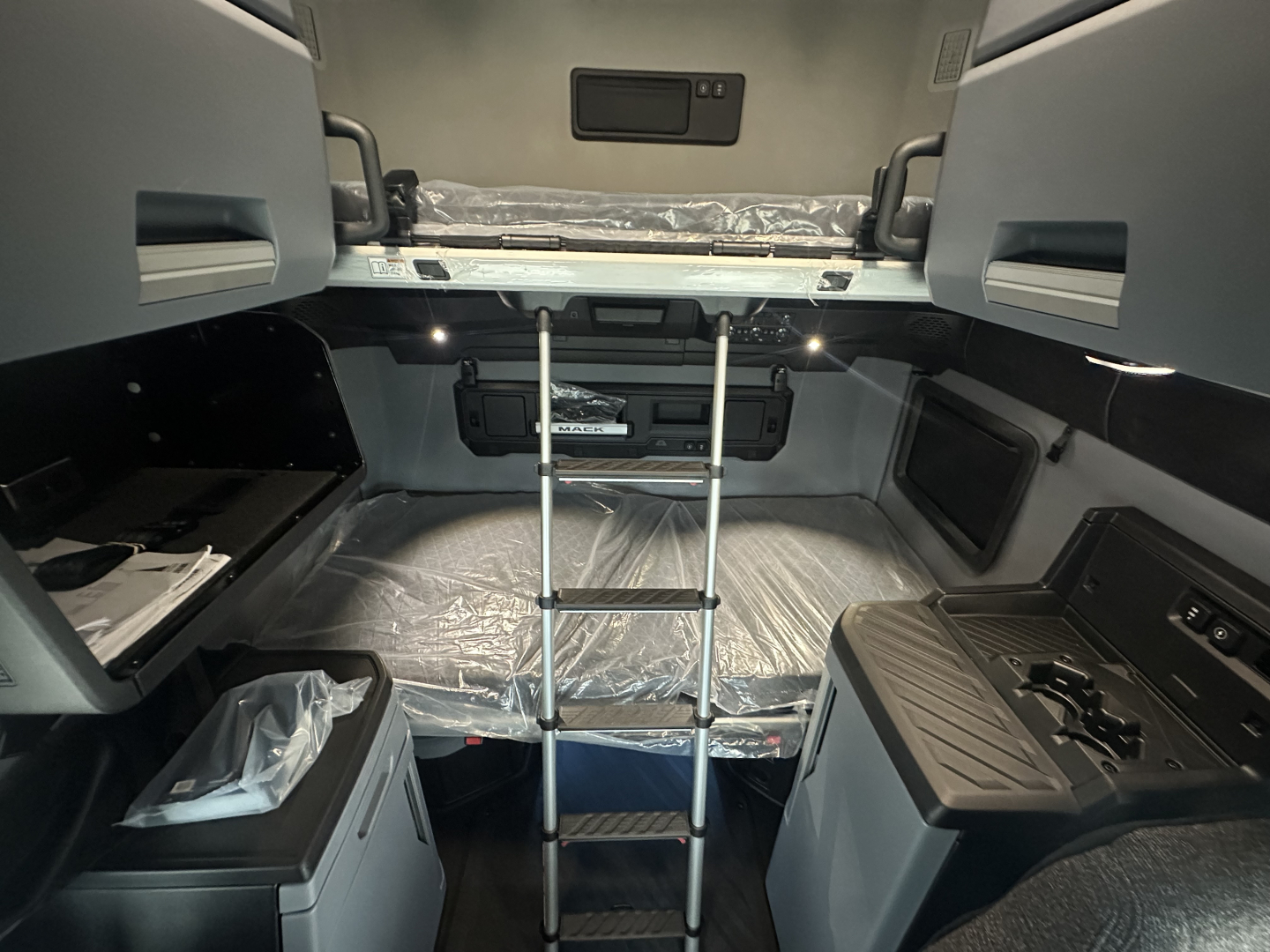 Interior of a new 2026 Mack PR64T76H sleeper cab showing upper bunk with ladder and control panels.
