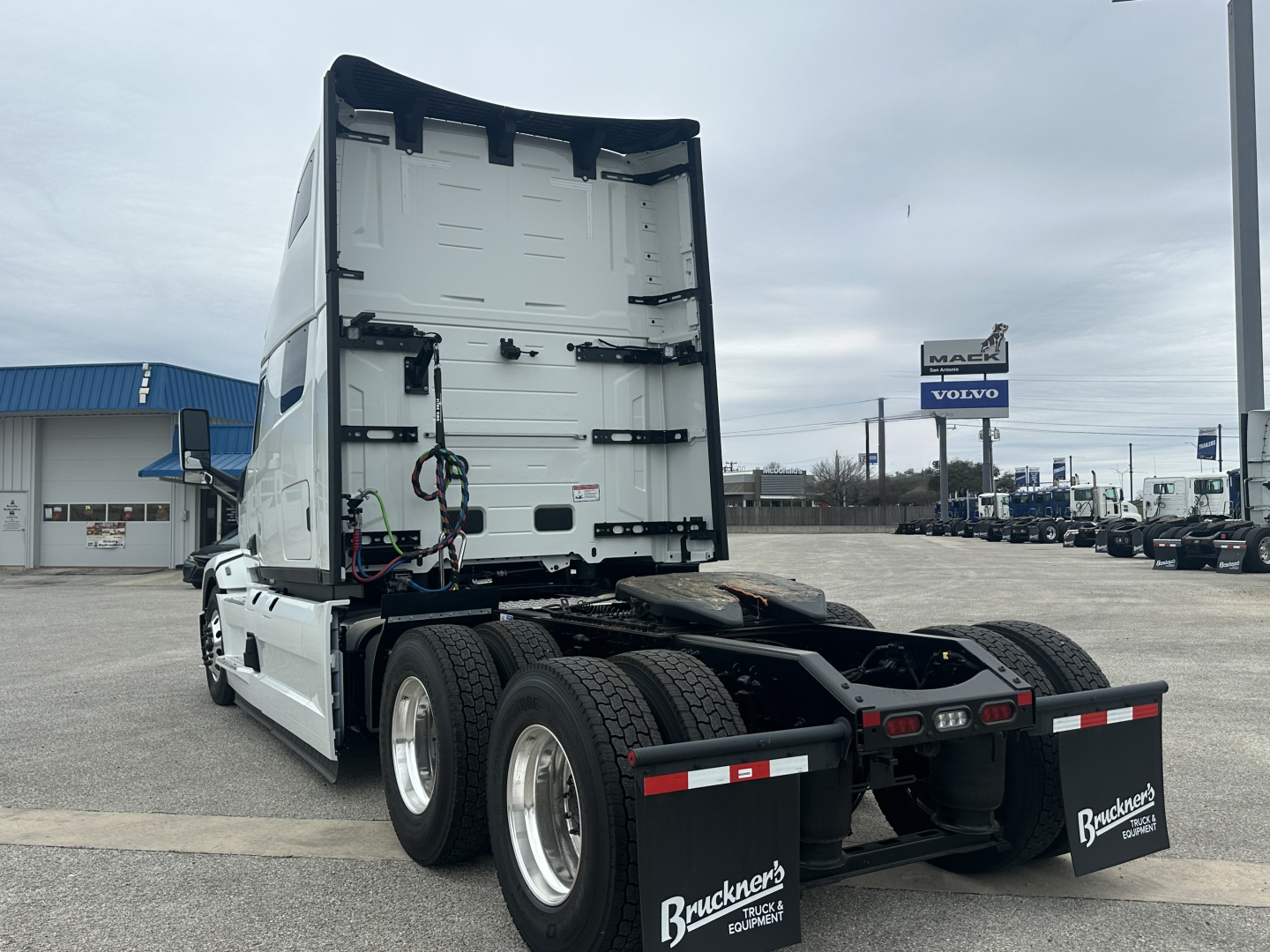 Truck cab rear view showing sleeper cab and chassis, with no visible text on the trailer side; rear mud flaps with Bruckner's logos.