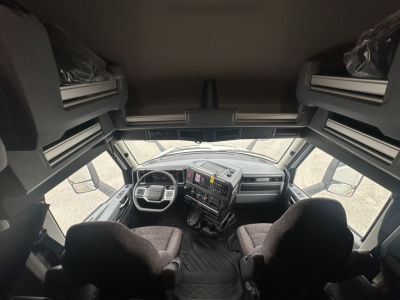 Cab interior of a new Mack PR64T76H truck showing steering wheel, dashboard, and seats.
