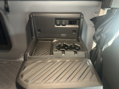 Cab interior center console showing cup holders and charging/auxiliary ports on the dash area, with a fold-out tray/table surface.