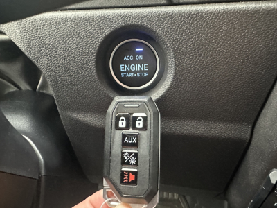 Engine start/stop button on dashboard and a hanging key fob with lock, unlock, auxiliary, and lighting controls visible.