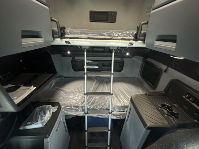 Interior of a new 2026 Mack PR64T76H sleeper cab showing upper bunk with ladder and control panels.