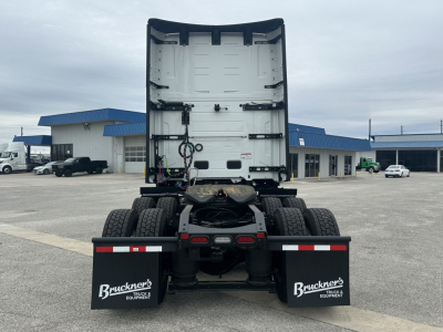 Rear view of a Mack PR64T76H tractor cab facing away showing fifth wheel, dual rear axles, mud flaps with Buckner's Equipment, and cab back with white exterior.