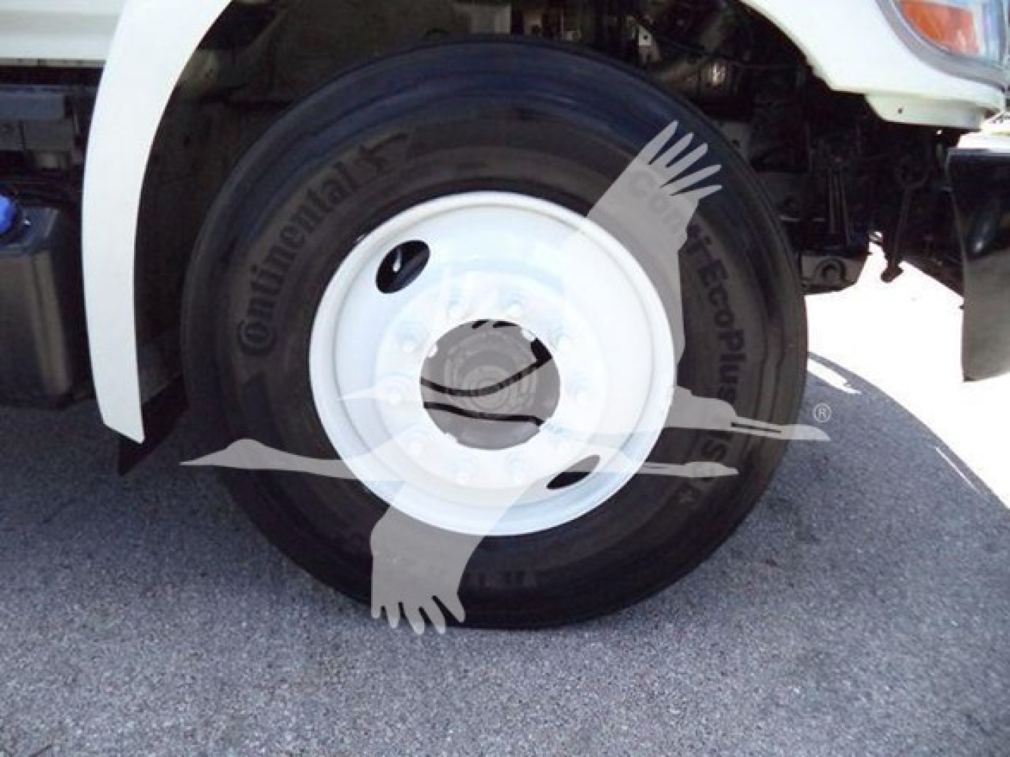 Truck wheel and front fender of a 2015 Hino 268A refrigerated truck showing Continental tire and white steel rim.
