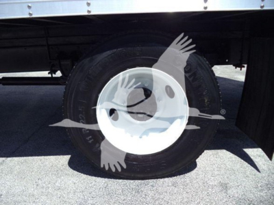 Truck wheel and tire on a refrigerated truck body showing a white steel rim and black tire.