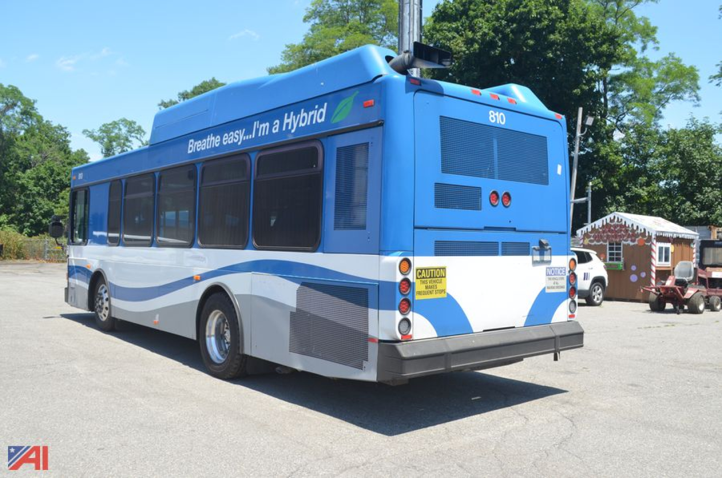 Blue 2011 Gillig Low Floor shuttle bus rear view showing ‘Breathe easy. I'm a Hybrid’ text on side, rear tail lights, and caution stickers.
