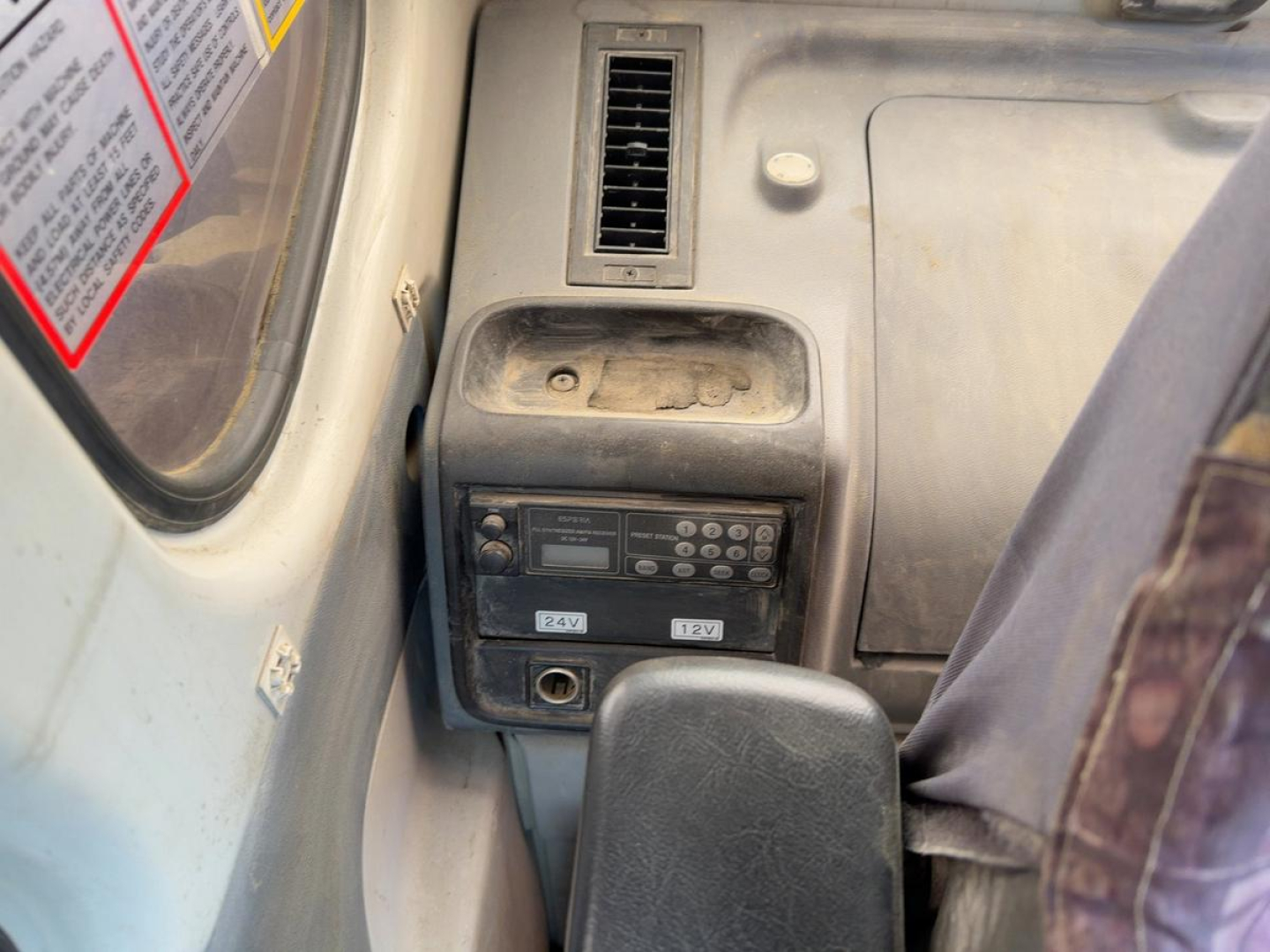Cab interior of a 2007 Link Belt 330LX excavator showing control panel with 24V. A vent above and a seat to the right.
