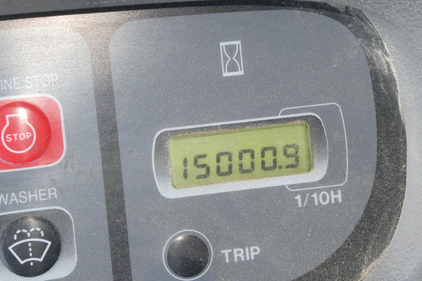 Calibration display showing 15000.9 hours on excavator control panel with STOP button and washer icons.