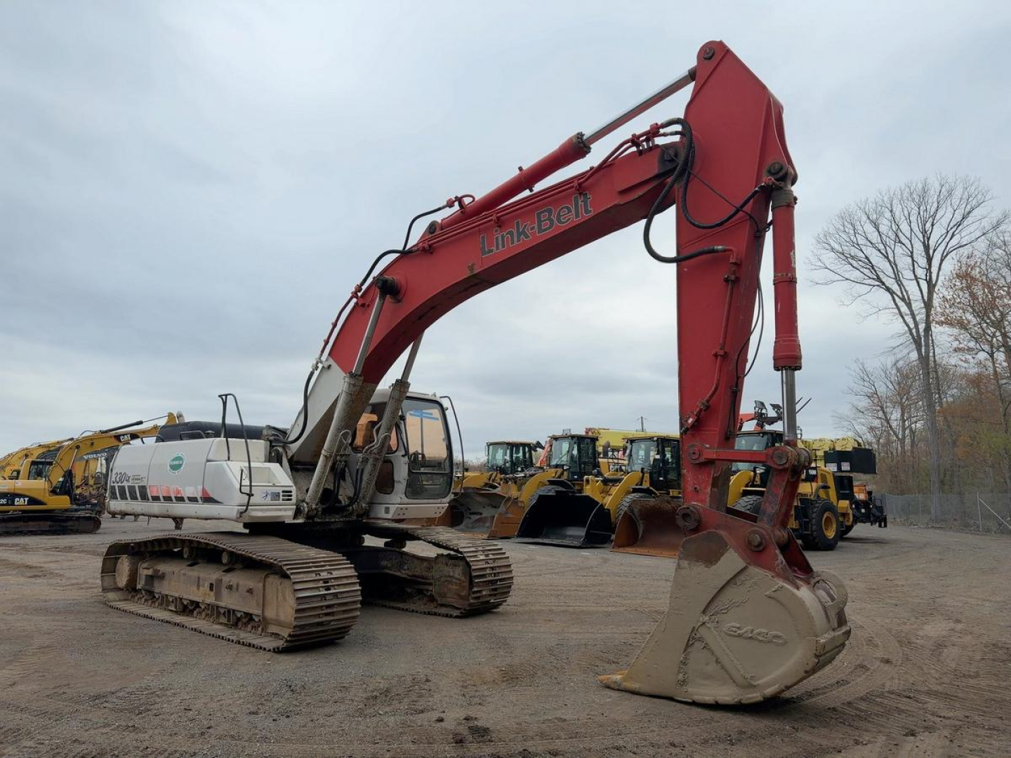 Excavator 2007 Link-Belt 330LX hydraulic arm and bucket in yard with other heavy equipment in background