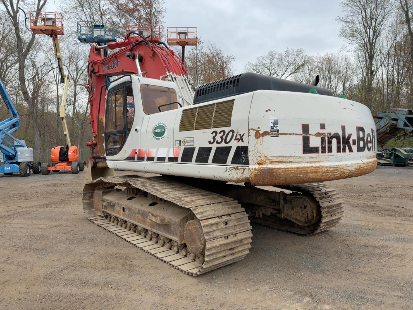excavator showing Link-Belt 330LX with tracked undercarriage and rear engine housing, white body with 330LX logo, rust and dirt on tracks.