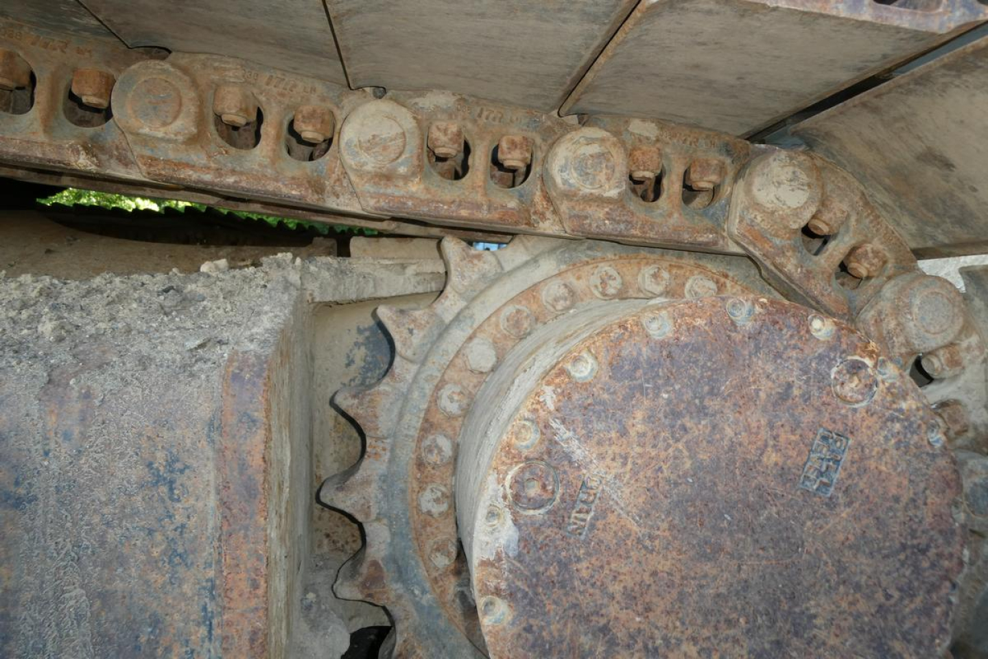Link Belt 330LX excavator track drive system with rusted sprocket and track links, close-up view of chain and rollers.