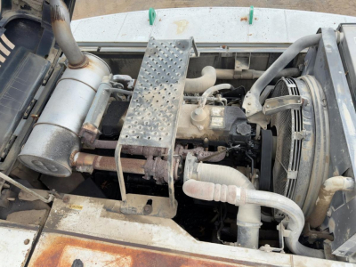 Link-Belt 330LX excavator engine bay showing exhaust system, radiator, hoses, and metal step plate; visible components include intake manifold, coolant hoses, and belt drive.