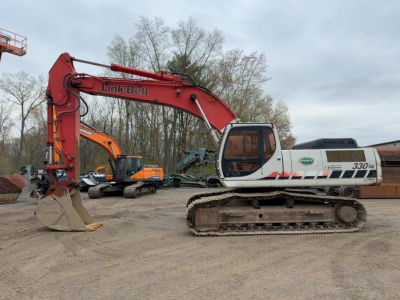 Mid-size Link-Belt 330LX excavator in a yard, orange-arm and white cab with tracks visible.