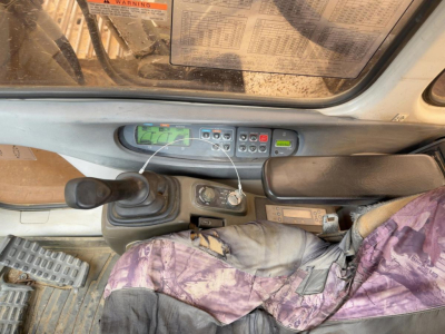 Cab interior of a Link Belt 330LX excavator showing control panel, joystick, pedals, and display screen.