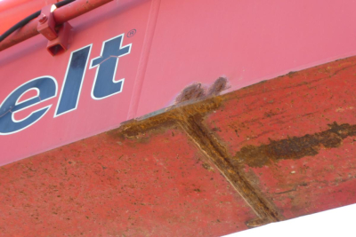  excavator side showing damaged undercarriage with 'elt' logo and rusted frame area
