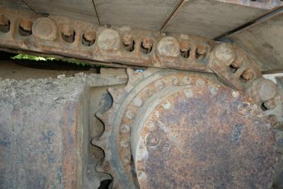 Link Belt 330LX excavator track drive system with rusted sprocket and track links, close-up view of chain and rollers.