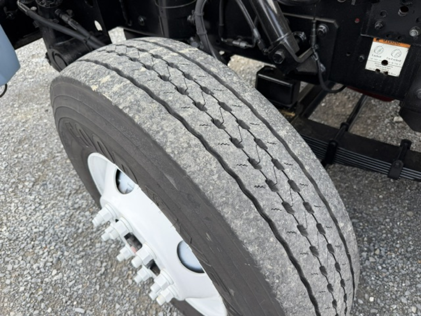 Truck front wheel view showing tire and white wheel hub with lug nuts.