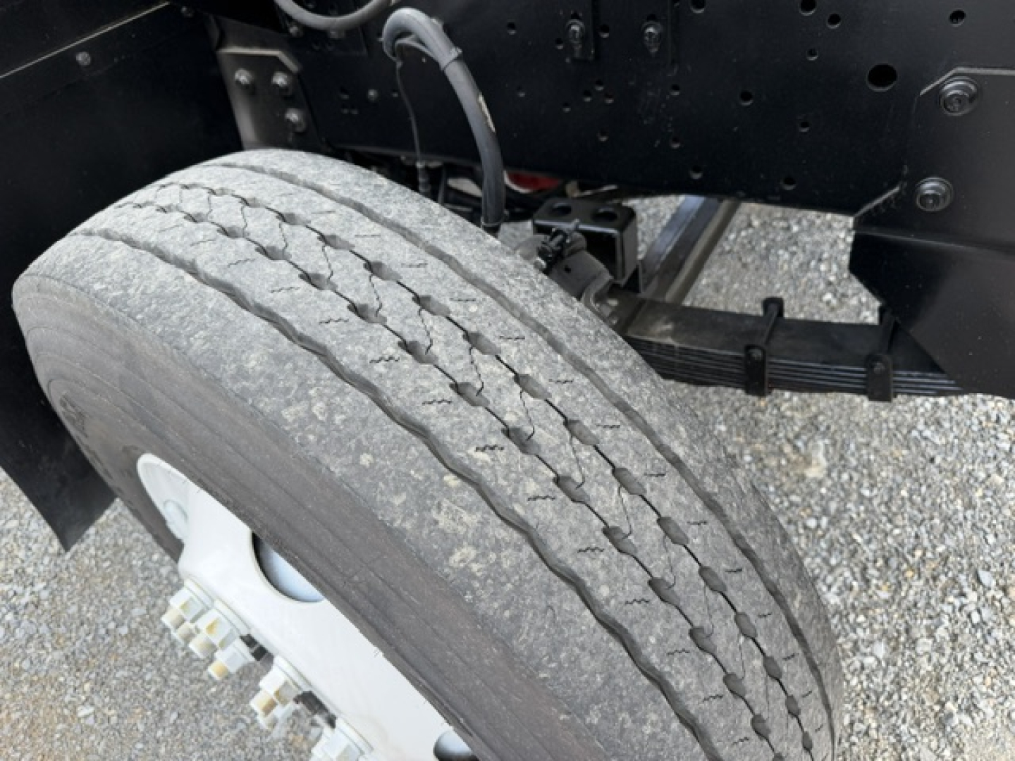 Truck rear dual axle showing worn front tire tread and wheel hub with lug nuts