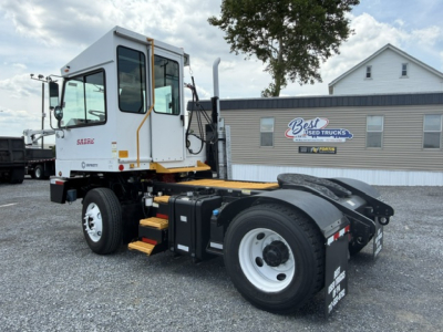 Truck chassis and cab showing Capacity Sabre DOT logo on door and wheel fender, with yard building in background.