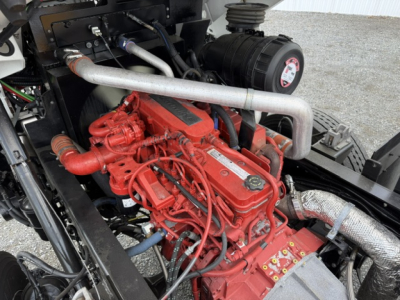 Capaciy Sabre diesel engine bay showing red engine block with numerous hoses, silver coolant pipe, and black air filter housing.