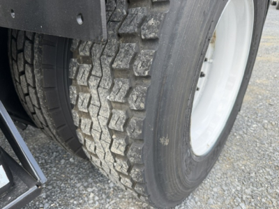 Tire and wheel of a heavy-duty truck showing tread pattern and nearby parts.