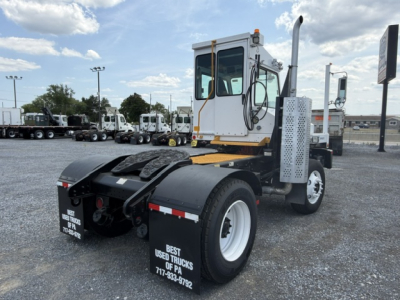 Tractor cab view of a white capacity Sabre DOT yard truck with large dual rear wheels and black fenders, showing fuel/air lines and demand label; photo focuses on cab and chassis.