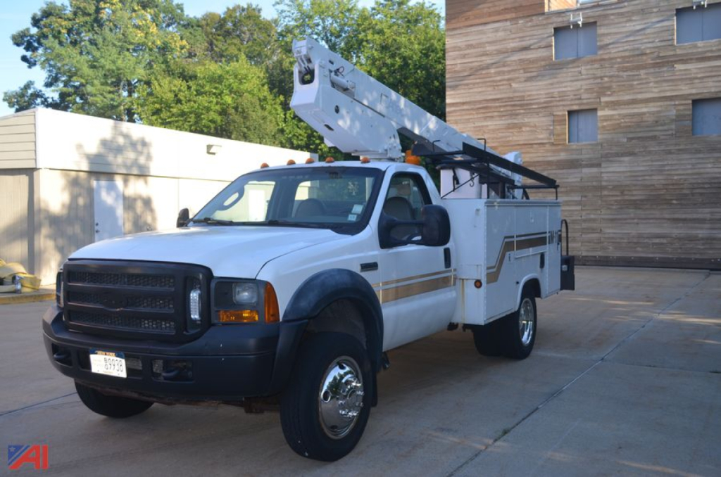 Ford F-550 utility truck with a boom lift on the bed, white with black front bumper, headlights, and extended boom mounted near cab. No visible text on the truck body.